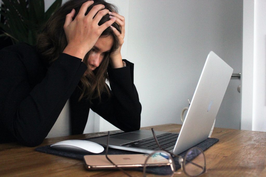 woman-covering-face-facing-laptop