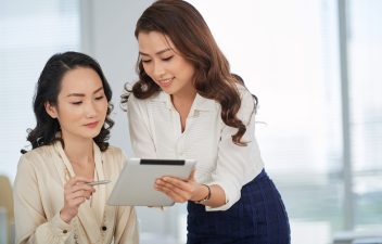 Lovely smiling business lady showing data on computer screen to colleague