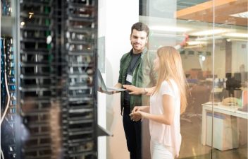 two-server-people-standing-in-server-room-configuring-servers